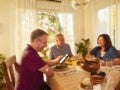 Una familia en la mesa del comedor comiendo y conversando.