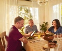 Una familia en la mesa del comedor comiendo y conversando.
